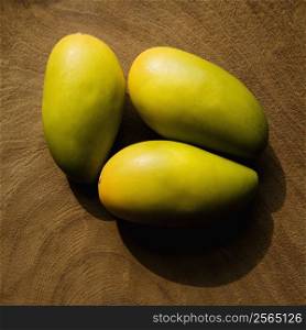 Still life of three wooden mangoes on plate.