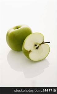 Still life of whole and sliced green apples on white background.