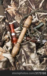 Still life shot of bird calls against camouflage clothing.