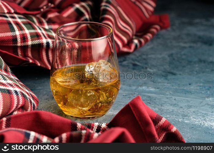Still-life with a glass of bourbon. A glass of whiskey with ice. Concept of autumn spleen.