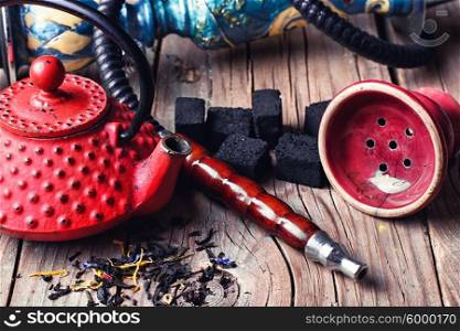 Still life with a hookah. Details of Smoking hookah and red metal kettle spilled tea leaf