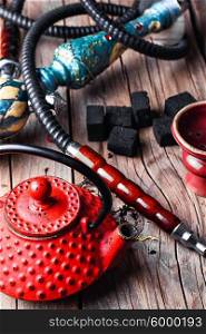 Still life with a hookah. Details of Smoking hookah and red metal kettle spilled tea leaf