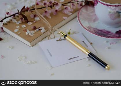 Still Life with a notebook ,a pen, spring branch,a cup of coffee , on the white table.