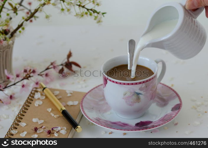 Still Life with a notebook ,a pen, spring branch,a cup of coffee , on the white table.