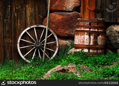 Still-life with an old wheel and barrel standing near the wall