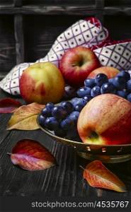 Still life with apples and grapes. Autumn harvest of apples and grapes on a dark background