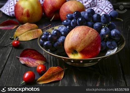 Still life with apples and grapes. Autumn harvest of apples and grapes on a dark background