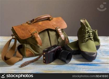 Still life with casual man,bag,shoes,wallet and camera on colored wooden table