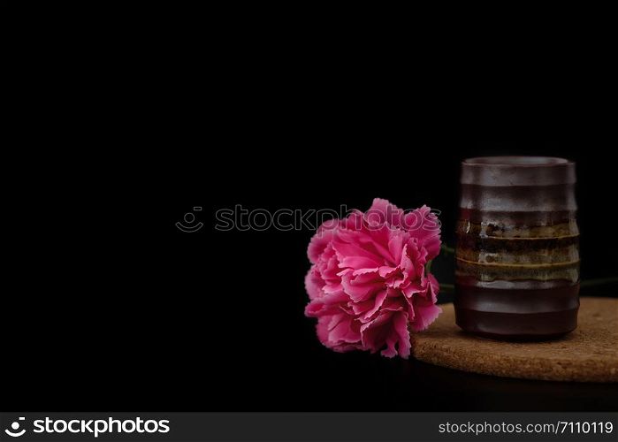 Still life with flower near the pottery vase on black background, Choose a focal point, copy space for write.