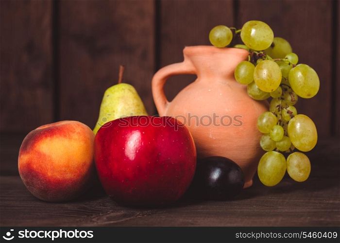 Still life with fruits and pitcher on the wooden table