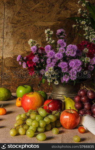 Still life with Fruits were placed together with a vase of flowers beautifully.