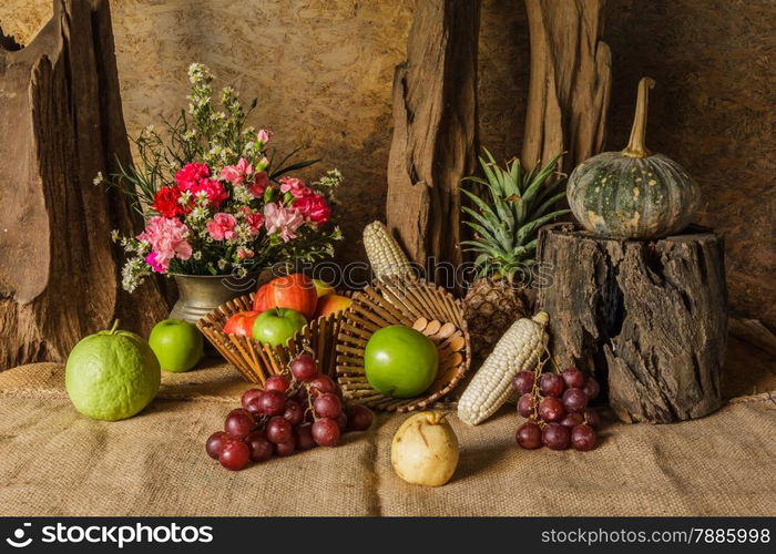 Still life with Fruits were placed together with a vase of flowers beautifully.