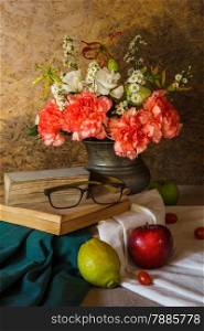 Still life with glasses resting on the book with fruits and flowers in a vase.