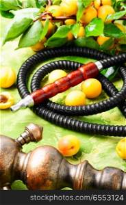 Still life with oriental smoking hookah and a branch of ripe apricots.Shisha Concept. Eastern shisha with apricot