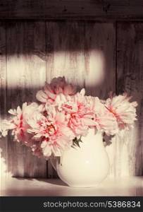 Still life with peonies over shabby wooden wall