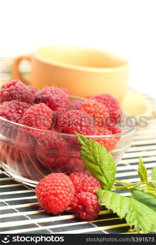 Still life with raspberries and green leafs on striped placemat with white copyspace, close up