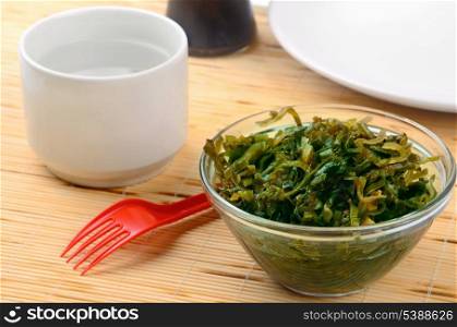 Still life with seaweed salad and cup of water