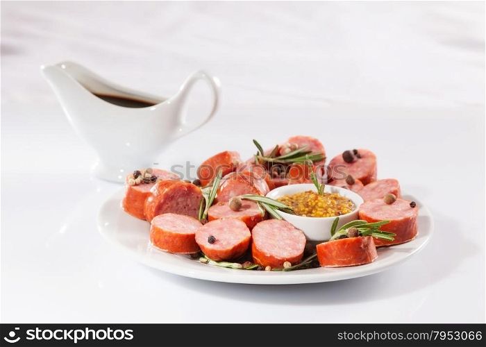 still life with sliced sausage, pepper, rosemary, sauce and mustard. on a white background