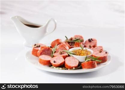 still life with sliced sausage, pepper, rosemary, sauce and mustard. on a white background