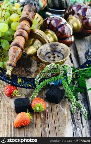 Still life with smoking hookah and grapes on wooden background. Smoking hookah is in the details