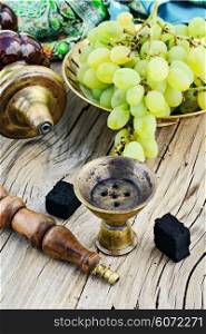 Still life with smoking hookah and grapes on wooden background. Smoking hookah is in the details