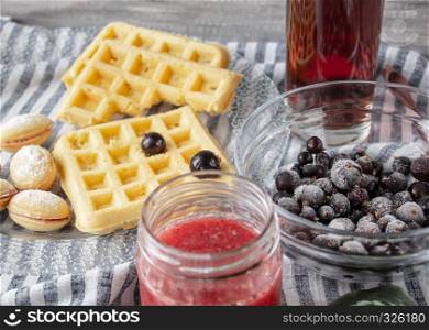 Still life with strawberry jam on the table with cookies on a bowl and frozen currant fruit. Still life with strawberry jam on a table with cookies in a bowl and currant fruit