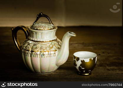 Still life with teapot on wooden table over grunge background