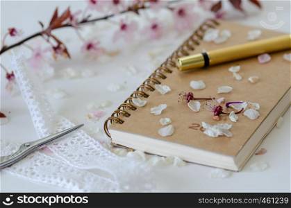 Stilllife with a notebook,pen and flower petals on the white background.