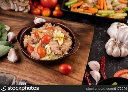 Stir cabbage with pork belly in a plate on a wooden plate.