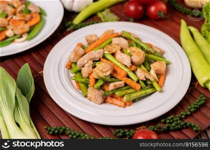 Stir-fried asparagus and carrots with pork in a white plate. Selective focus.