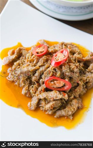 stir fried beef with curry sauce and red peppers on a white plate. stir fried beef