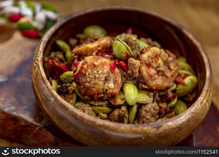 Stir Fried Bitter beans (Sator) with Shrimp in wooden bowl, It is a traditional food of southern Thailand, Spicy, stink bean, Selective focus.