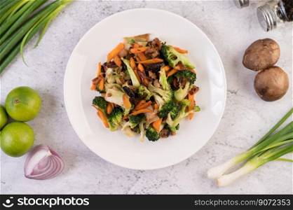 Stir-fried broccoli, carrots, and mushrooms with pork in a white dish.