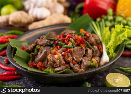 Stir-fried chicken liver basil on banana leaves in a black dish. Thai food.