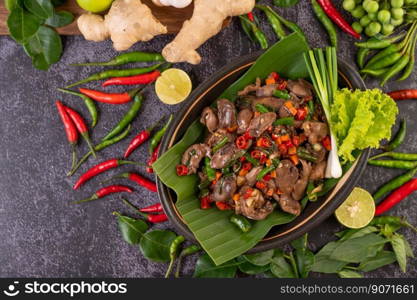 Stir-fried chicken liver basil on banana leaves in a black dish. Thai food.