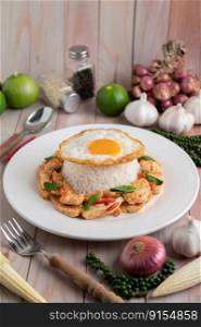 Stir Fried Chili Paste Chicken with Rice Fried eggs in white plate on wooden table.