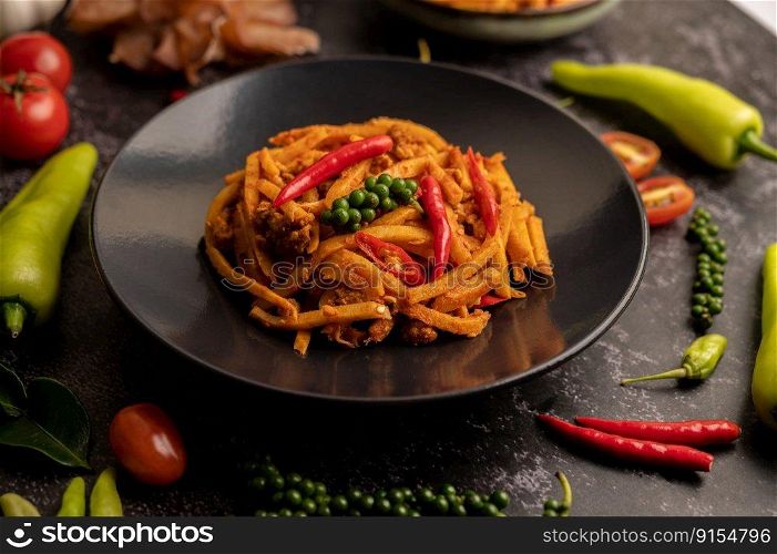 Stir Fried Curry Paste with Bamboo Shoot and Minced Pork, and spices on a black cement floor