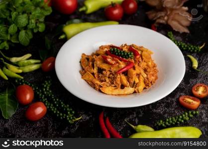 Stir Fried Curry Paste with Bamboo Shoot and Minced Pork, and spices on a black cement floor