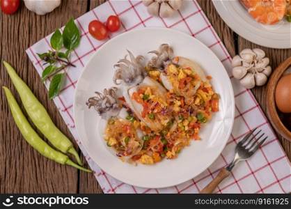 Stir fried glass noodles with squid in a plate on red white cloth
