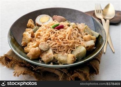 Stir fried instant noodles with green curry with chicken  Kaeng khiao wan  and Boiled egg in sweet brown sauce in ceramic bowl served with cutlery set. Easy noodle thai food, Selective focus.