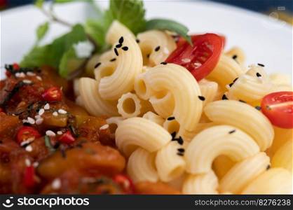 Stir-fried macaroni with tomato, chili, pepper seeds and basil in a white dish.