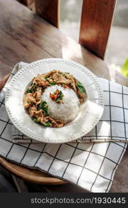 Stir-fried meat with chili and basil served with steamed rice on white dish. Stir-fried meat with chili and basil