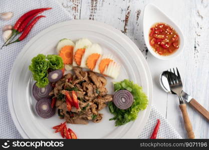 Stir fried pork basil on a white plate with carrots, Cucumber and Onion. Selective focus