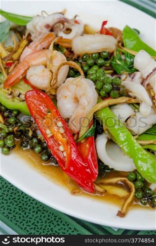 stir fried seafood with herbs and mix vegetable on white dish