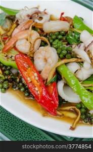 stir fried seafood with herbs and mix vegetable on white dish