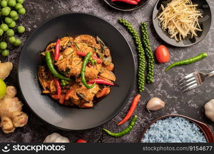 Stir-fried spicy Catfish in black plate with spices on black cement.