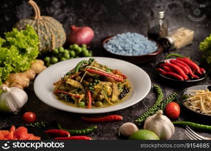Stir Fried Spicy Chicken in white plate with spices on black cement.
