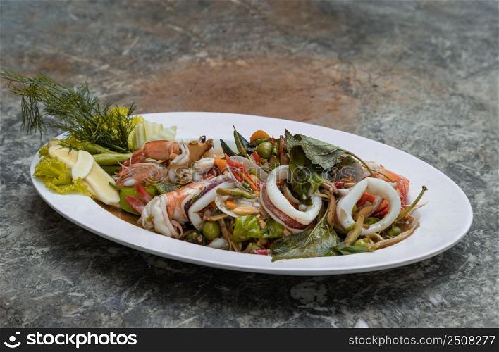 Stir-Fried Spicy seafood with herbs and spices served on white plate. Authentic thai food. Copy space, Selective focus.
