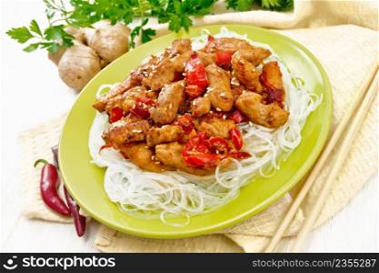 Stir-fry chicken with pepper, garlic, ginger and soy sauce sprinkled with sesame seeds in a plate, towel and parsley on light wooden board background