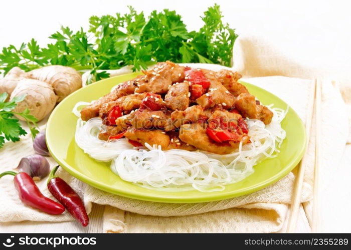 Stir-fry chicken with pepper, garlic, ginger and soy sauce, sprinkled with sesame seeds in a plate, napkin and parsley on white wooden board background